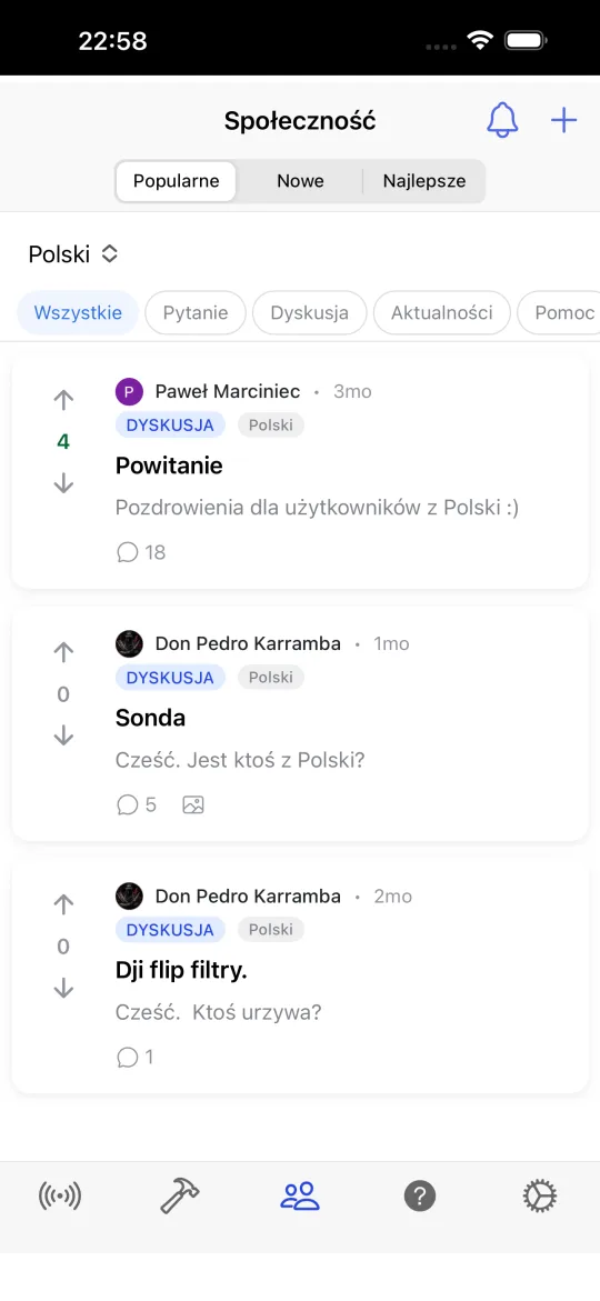 Ekran społeczności z postami sortowanymi według popularnych, nowych i najlepszych, tagami pytanie, dyskusja, wiadomości, pomoc i prezentacja oraz filtrem języka.